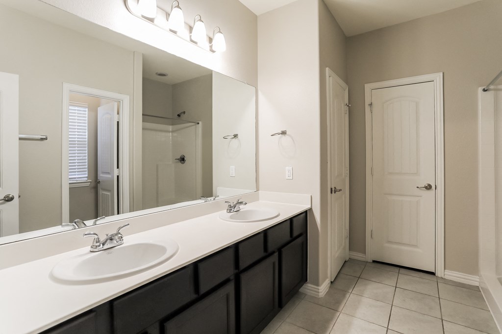 an empty bathroom with two sinks and a large mirror