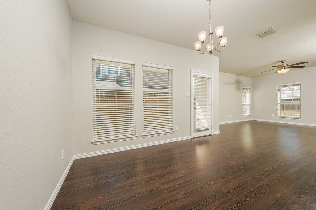 an empty living room with windows and a ceiling fan