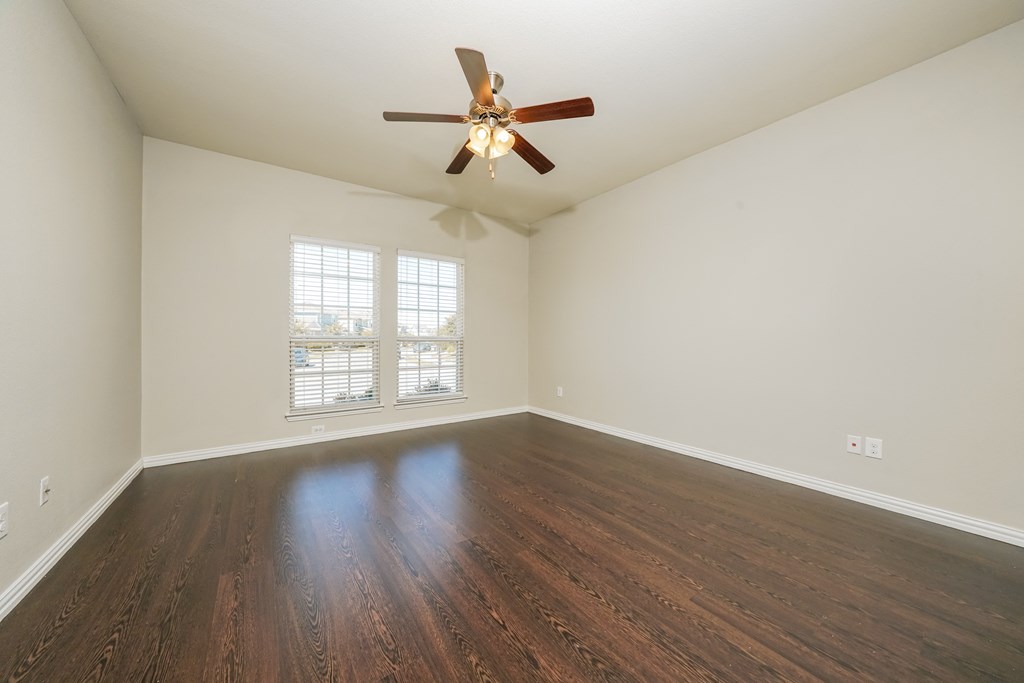 an empty living room with a ceiling fan and a window
