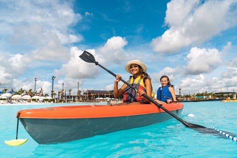 Two people are kayaking in a bright blue water body.