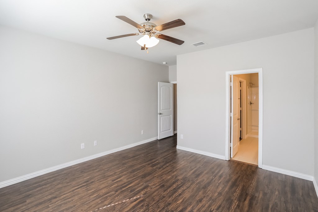 an empty living room with a ceiling fan and wood flooring