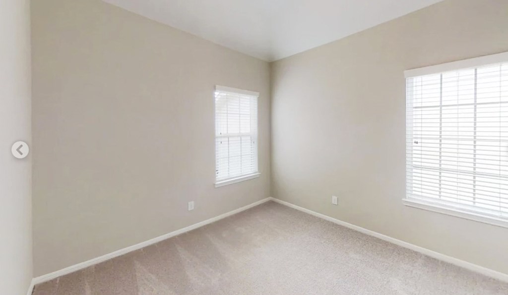 the living room of an empty home with two windows