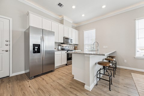 A kitchen with a refrigerator, microwave, and stove top oven.