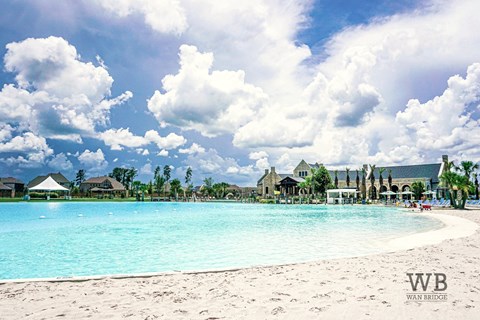 A beautiful beach scene with a pool and buildings in the background.