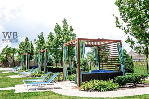 A row of blue lawn chairs are arranged in front of a wooden pavilion.