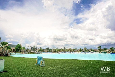 A large outdoor swimming pool with a blue tinted water and a white chair in the foreground.