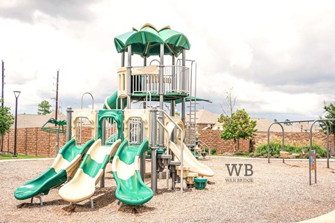 A playground with a green and yellow slide and a wooden structure.