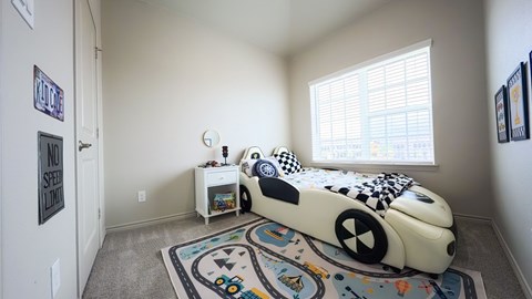 A child's bedroom with a white bed and a rug with a car design on it.
