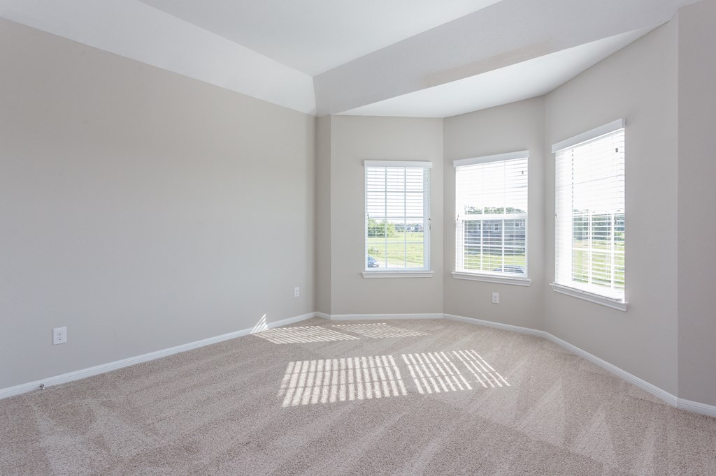 an empty room with carpet and three windows