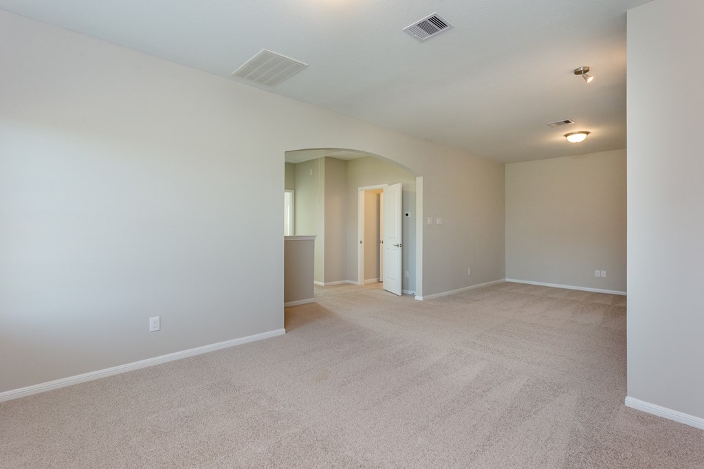 an empty living room with carpet and a door to a hallway