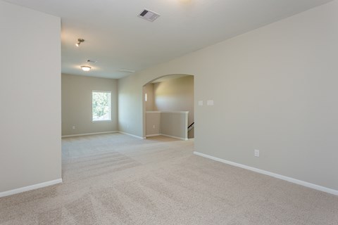 an empty living room and dining room with carpeting and a window