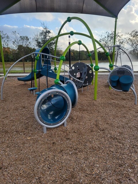 A playground with a blue slide and a green climbing frame.