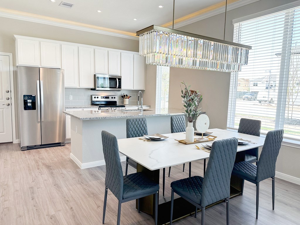 a kitchen with white cabinets and a white table with blue chairs at Enclave at Mason Creek, Katy,Texas