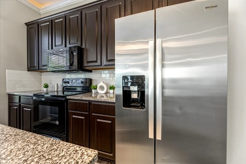 A kitchen with a stainless steel refrigerator and black cabinets.