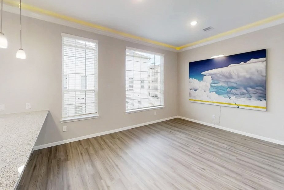 an empty living room with wood floors and a painting on the wall