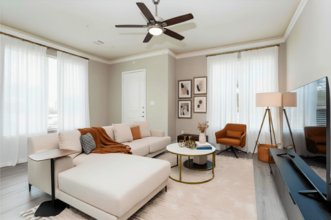 A living room with a white sofa, a coffee table, and a ceiling fan.