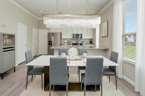A modern dining room with a large table and grey chairs.