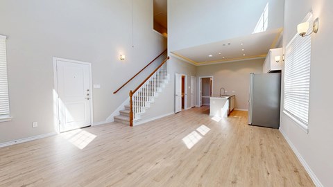 A spacious room with wooden floors and a staircase.