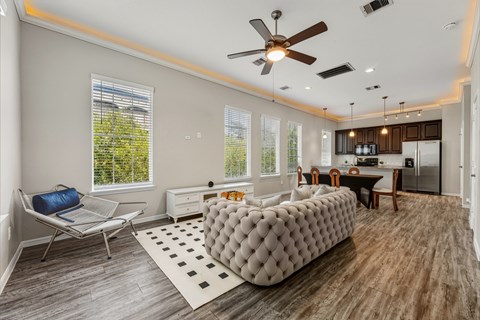A modern living room with a grey tufted sofa and a wooden floor.