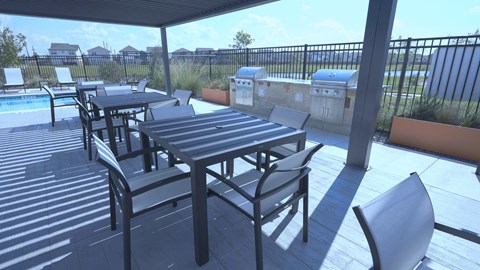 A patio with a table and chairs overlooking a pool.