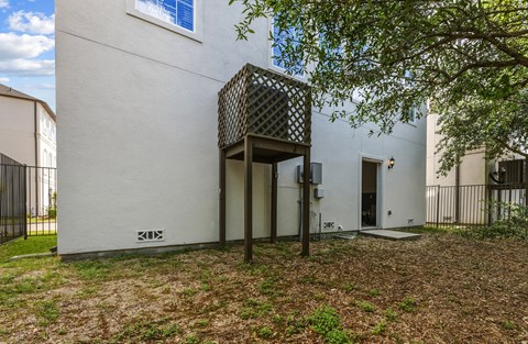 A white building with a black gate and a tree in front.