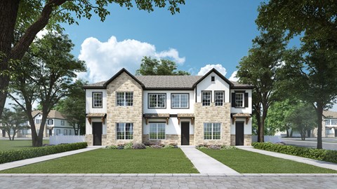 A large, two-story house with a stone facade and a gabled roof is surrounded by a well-manicured lawn and mature trees.