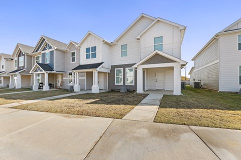 A row of modern houses with white exteriors and dark roofs.