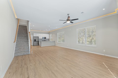 A spacious room with a staircase and a ceiling fan.