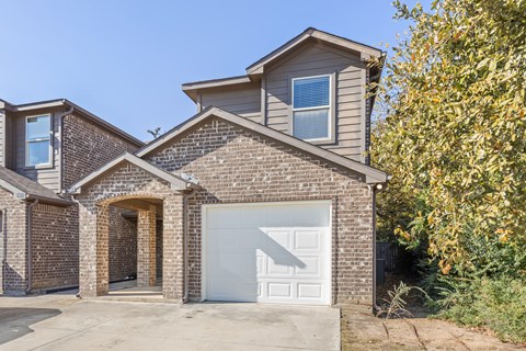 A house with a white garage door and a brick facade.