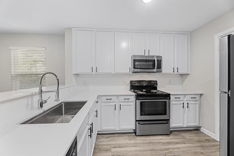 A kitchen with white cabinets and a black stove top oven.