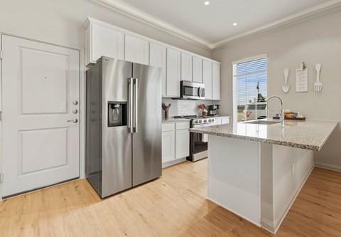 A modern kitchen with a stainless steel refrigerator and white cabinets.