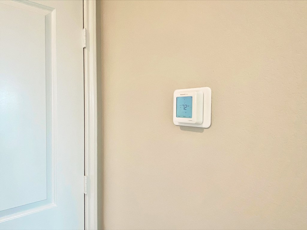 a white thermostat on a wall next to a door