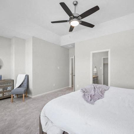 a bedroom with a white bed and a ceiling fan