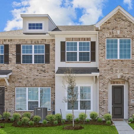 a brick house with a black door and a lawn
