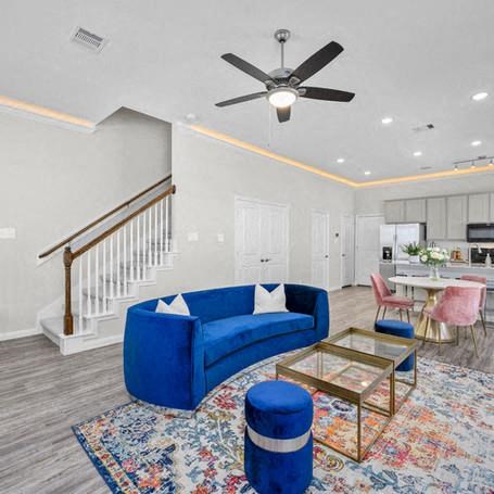 a living room with a blue couch and a ceiling fan