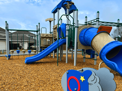 A playground with a blue slide and a grey elephant toy.