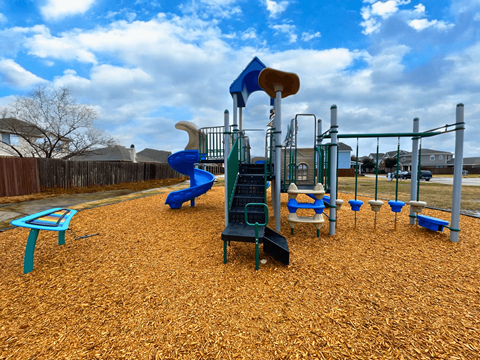 A playground with a blue slide and a green climbing frame.