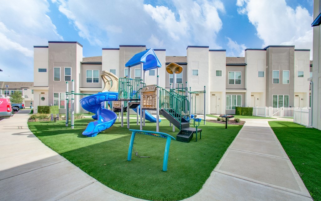 a playground with a blue slide in front of an apartment building at Enclave at Mason Creek, Katy,Texas