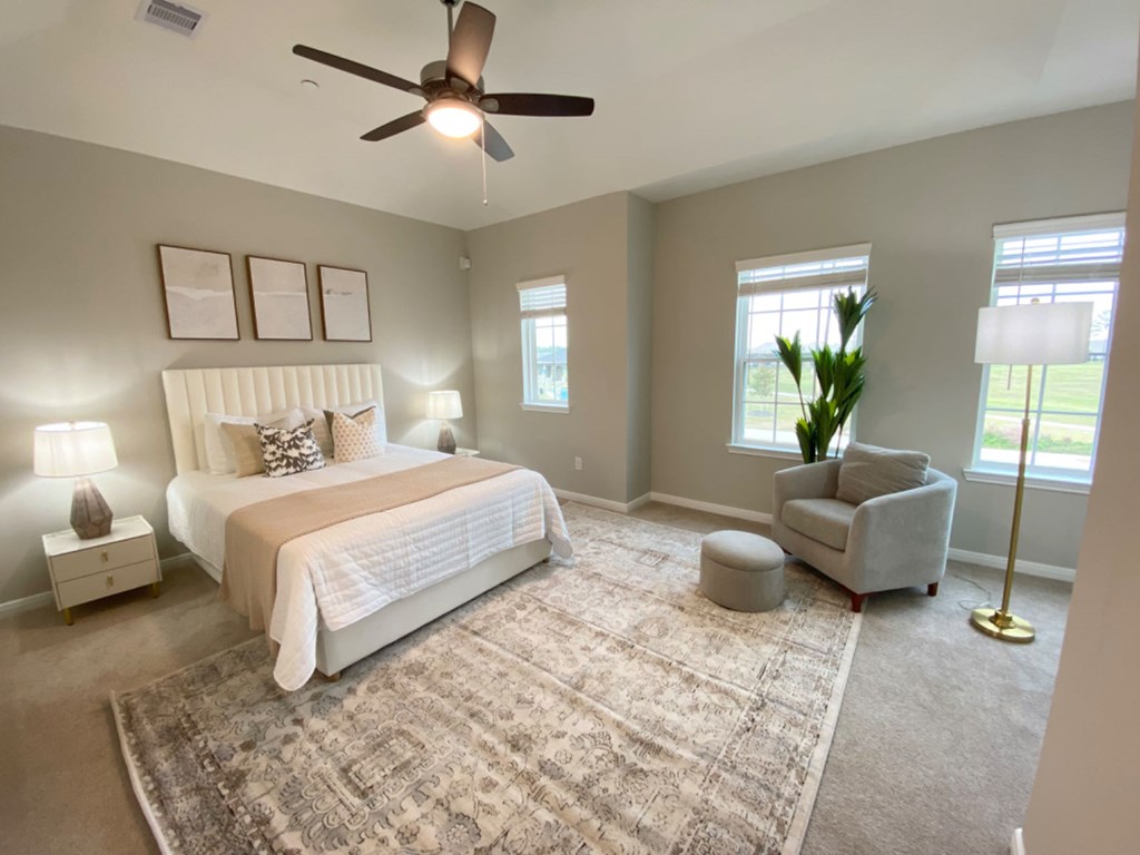 A bedroom with a large bed, a chair, and a rug.
