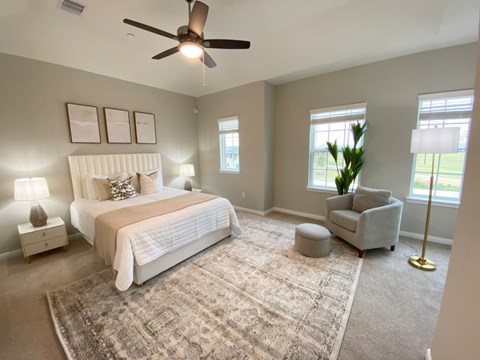 A bedroom with a large bed, a chair, and a rug.