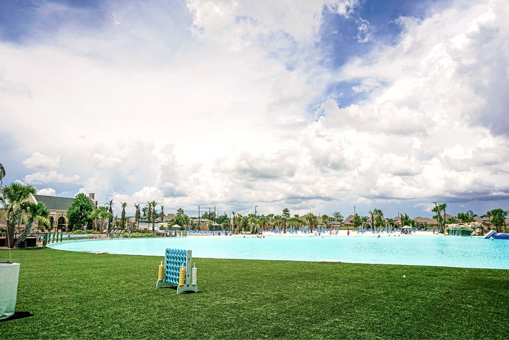 A blue swimming pool with a green lawn and a white chair.