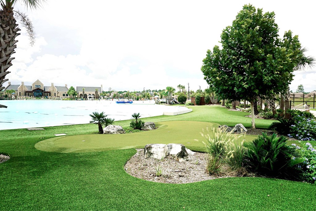 A golf course with a green and a tree.