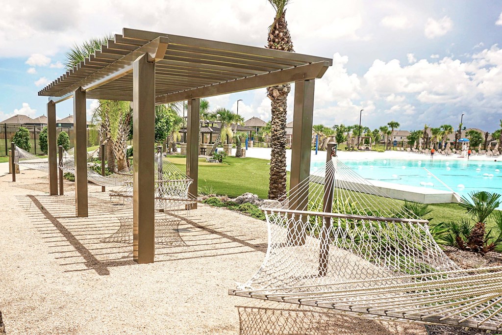 A wooden pergola with a palm tree in the middle of a poolside area.