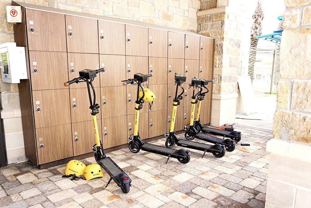 A row of yellow scooters are parked in front of a wooden wall.