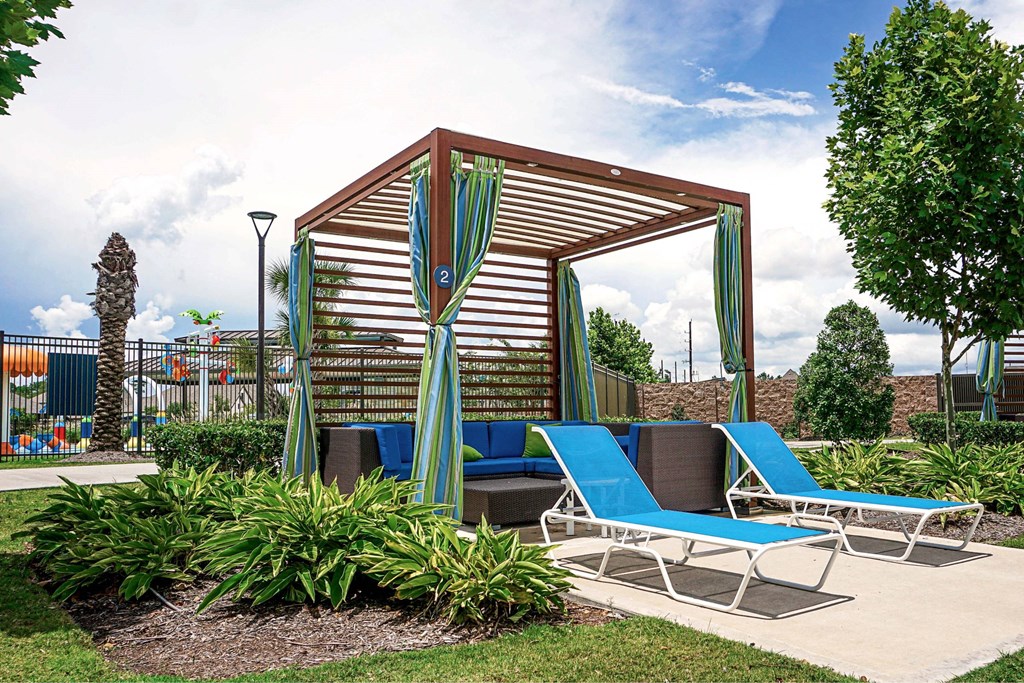 A wooden pavilion with a striped awning and blue lounge chairs.