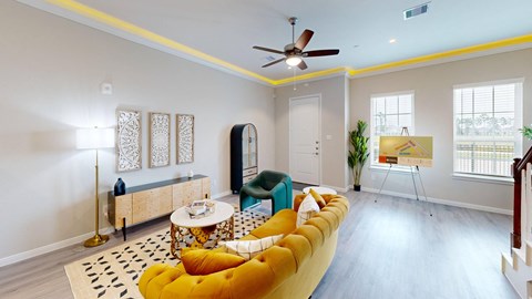 A living room with a yellow sofa and a black and white rug.