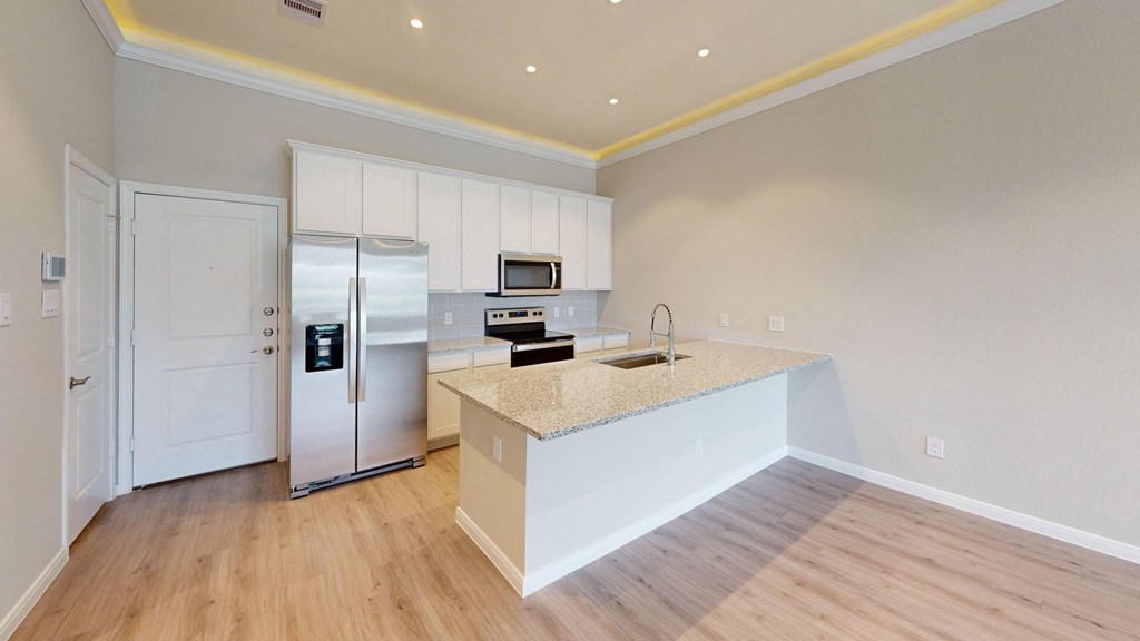 A kitchen with a refrigerator, microwave, and oven.