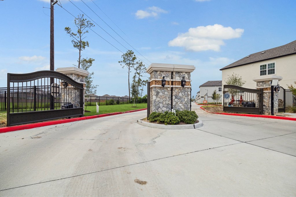 A gated entrance to a residential area with a stone pillar in the center.