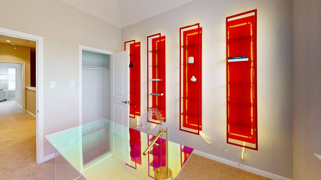 A hallway with three red doors and a glass table in the middle.