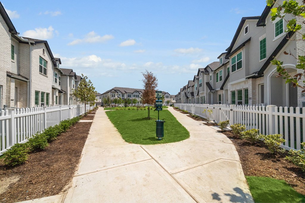 A long, narrow sidewalk separates a row of houses.